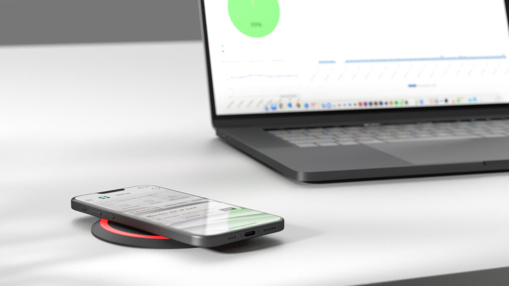 Phone charging on a Your Workcharge Puk with the management platform on a laptop in the background.