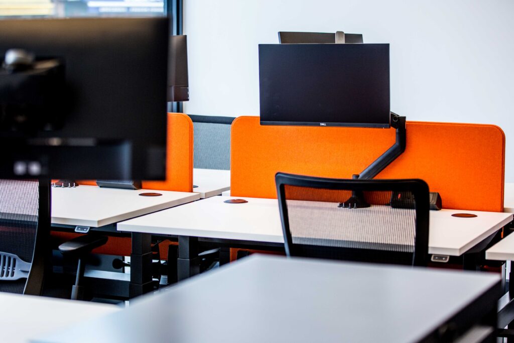 Sit stand desk with screens on monitor arms.
