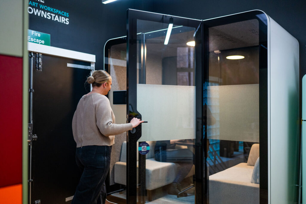 Person opening the door to enter a meeting pod in the Your Workspace showroom.