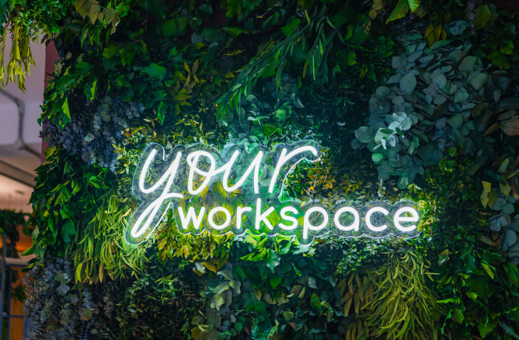 Your Workspace neon logo against a foliage wall.