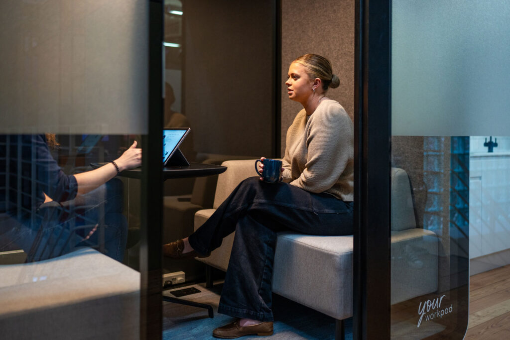 Two people having a meeting inside a meeting pod in the Your Workspace showroom.
